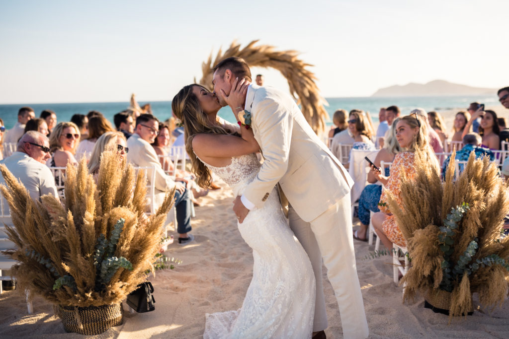 bride and groom kissing during beach wedding ceremony in Cabo