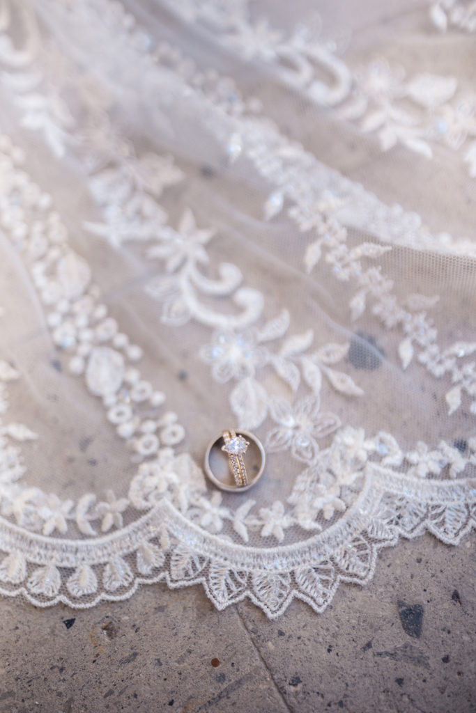 Wedding rings sitting on lace train of wedding dress