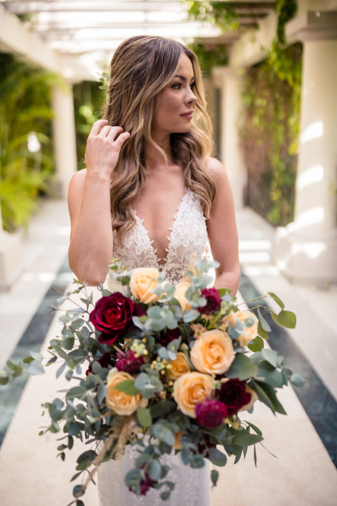 bride with red and peach flowers at dreams los cabos resort