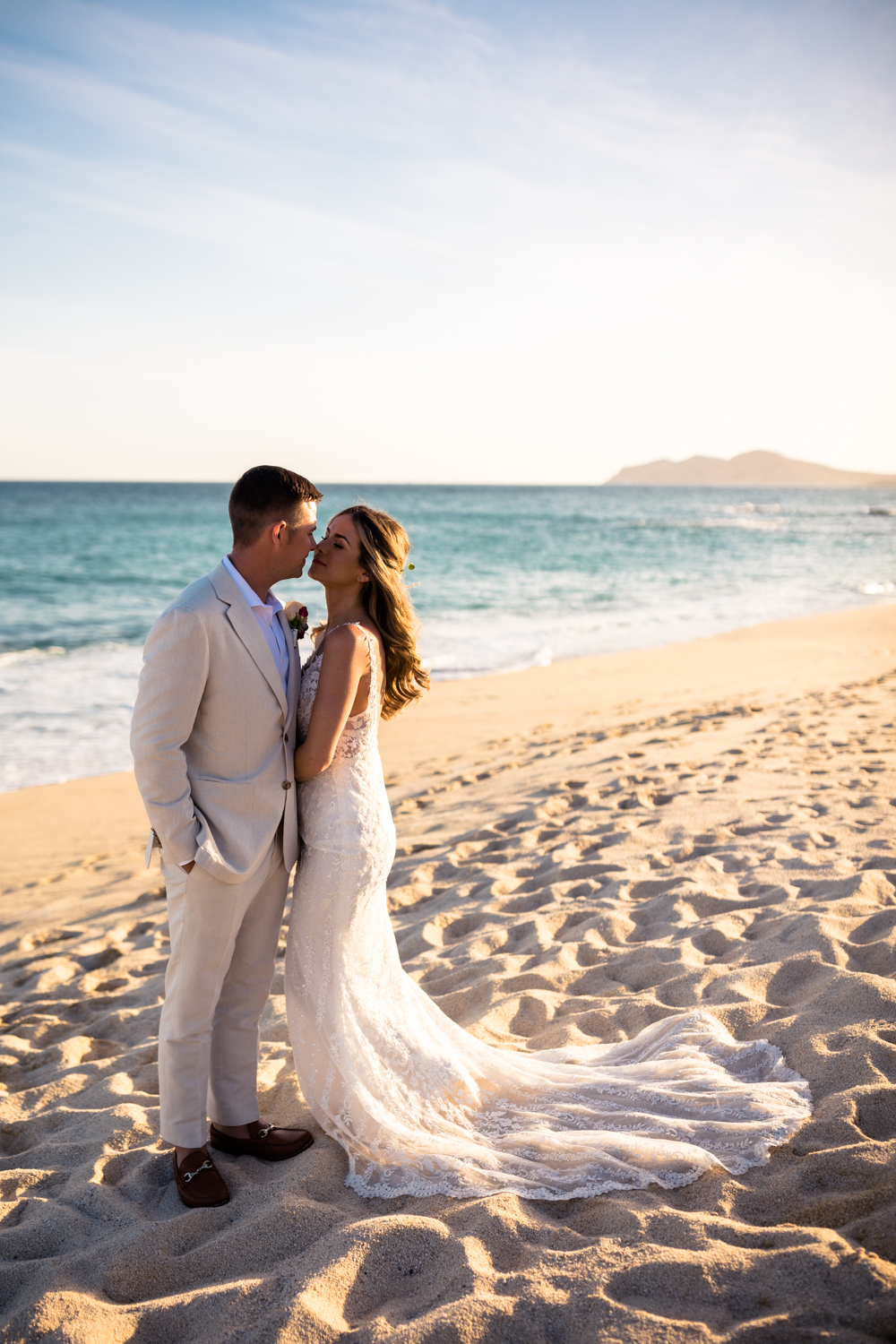 bride and groom kissing in front of ocean in cabo