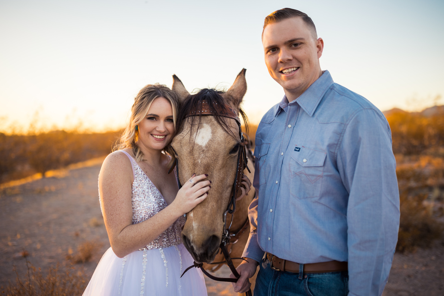Bride and groom smile while holding a horse close during their horse wedding photographed by Makayla McGarvey.