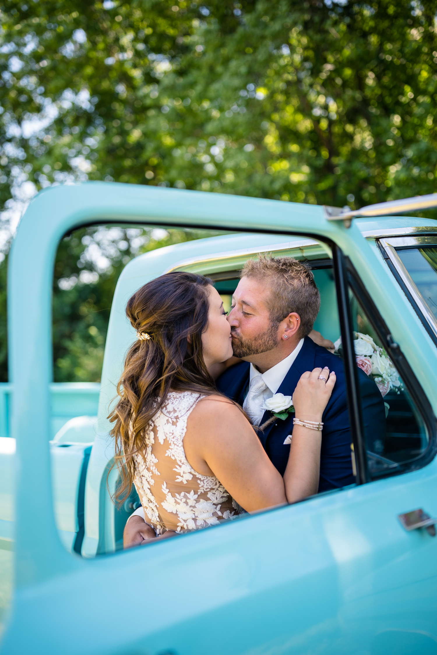The Ultimate Ranch Wedding Planning Guide (2021). Bride and groom share a kiss in a baby blue truck.