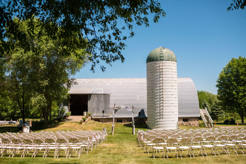  A ranch wedding ceremony set up in front of a barn and silo