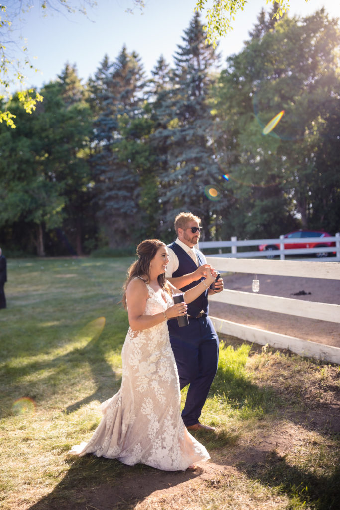 Couple walking hand-in-hand by the fence at their ranch wedding location