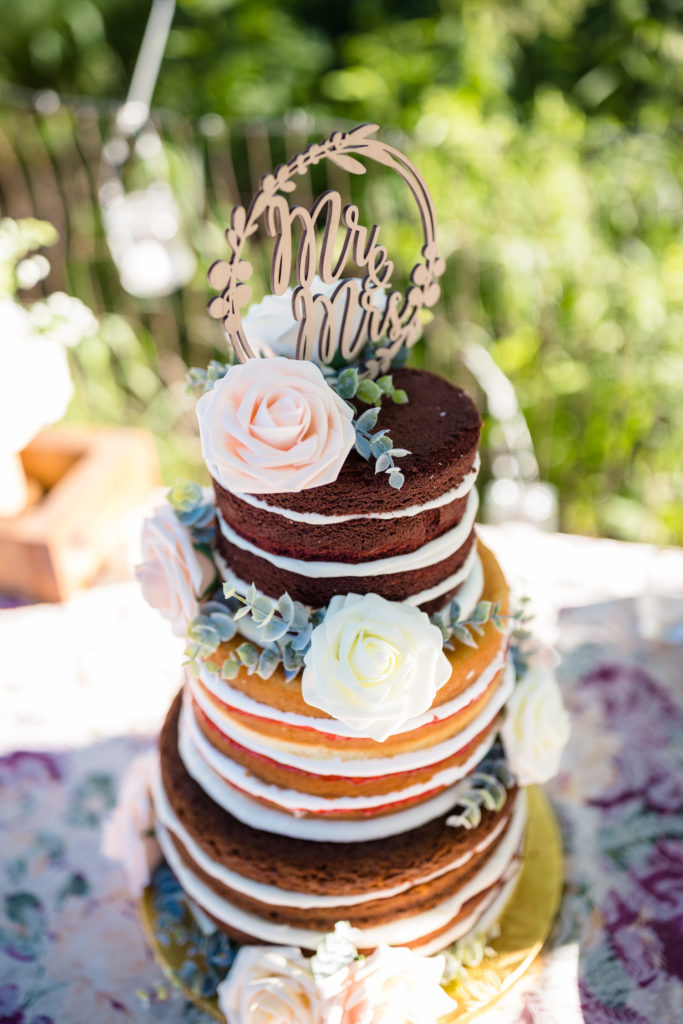 The Ultimate Ranch Wedding Planning Guide (2021). Close up photo of the three-layer wedding cake with floral embellishments and a Mr. and Mrs. topper