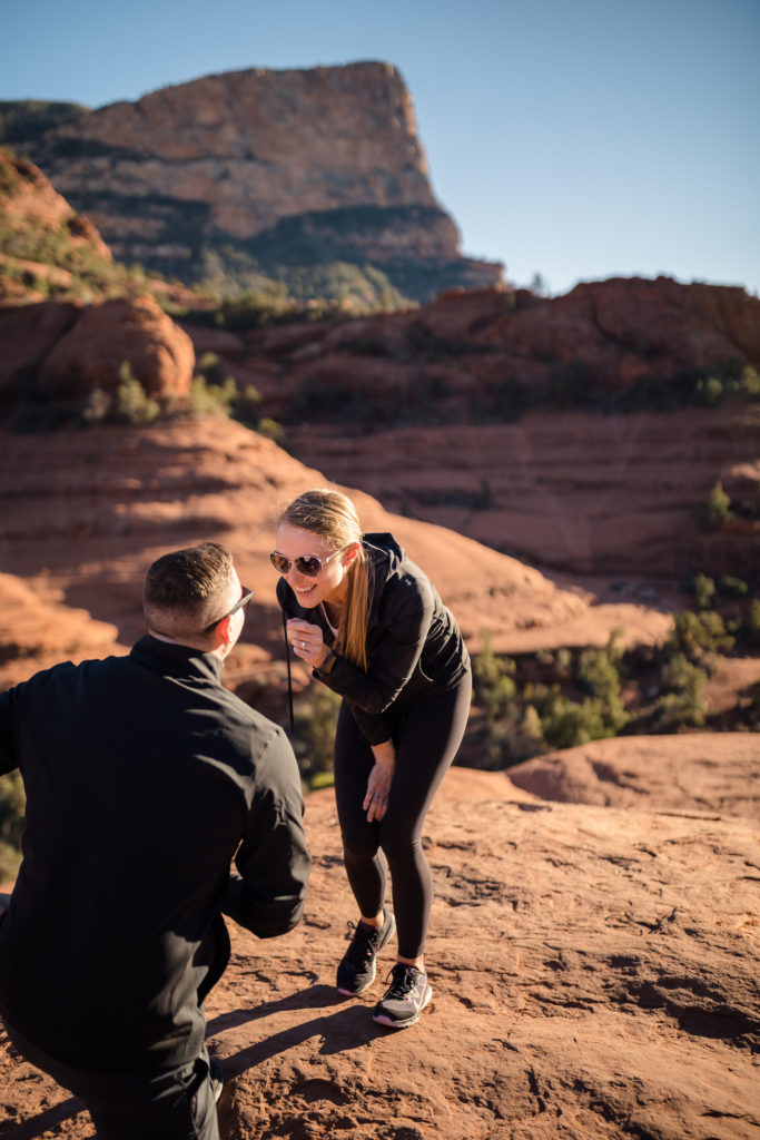 Guy getting down on one knee as he proposes to his girl at the Grand Canyon