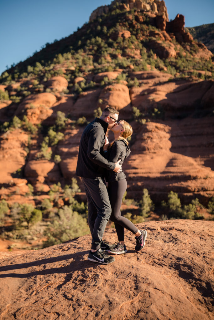 Newly engaged couple sharing a kiss during their Grand Canyon Proposal, taken by Makayla MacGarvey