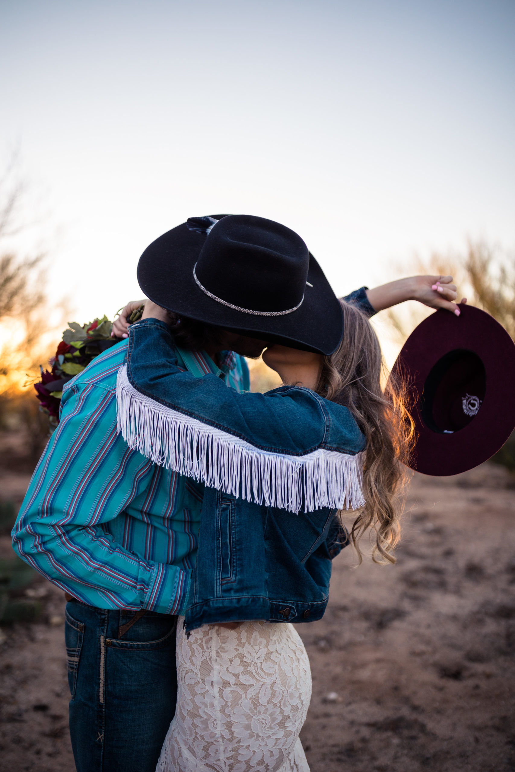 bride and groom kissing under cowboy hats