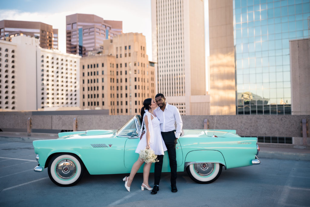 couple in front of sky scrappers with classic car