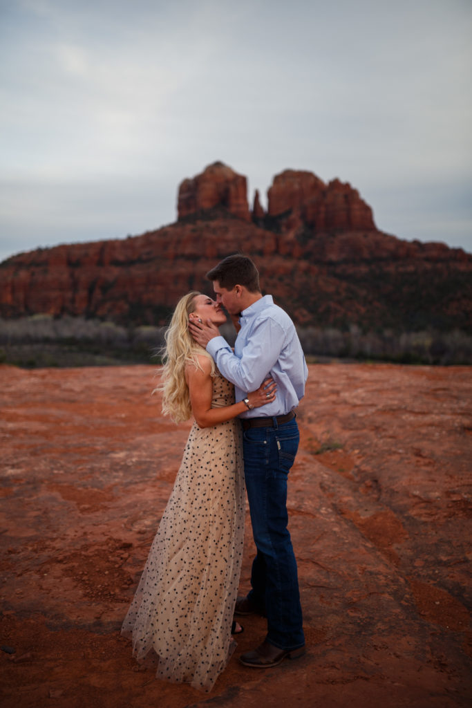 couple kissing in front of cathedral rock in sedona