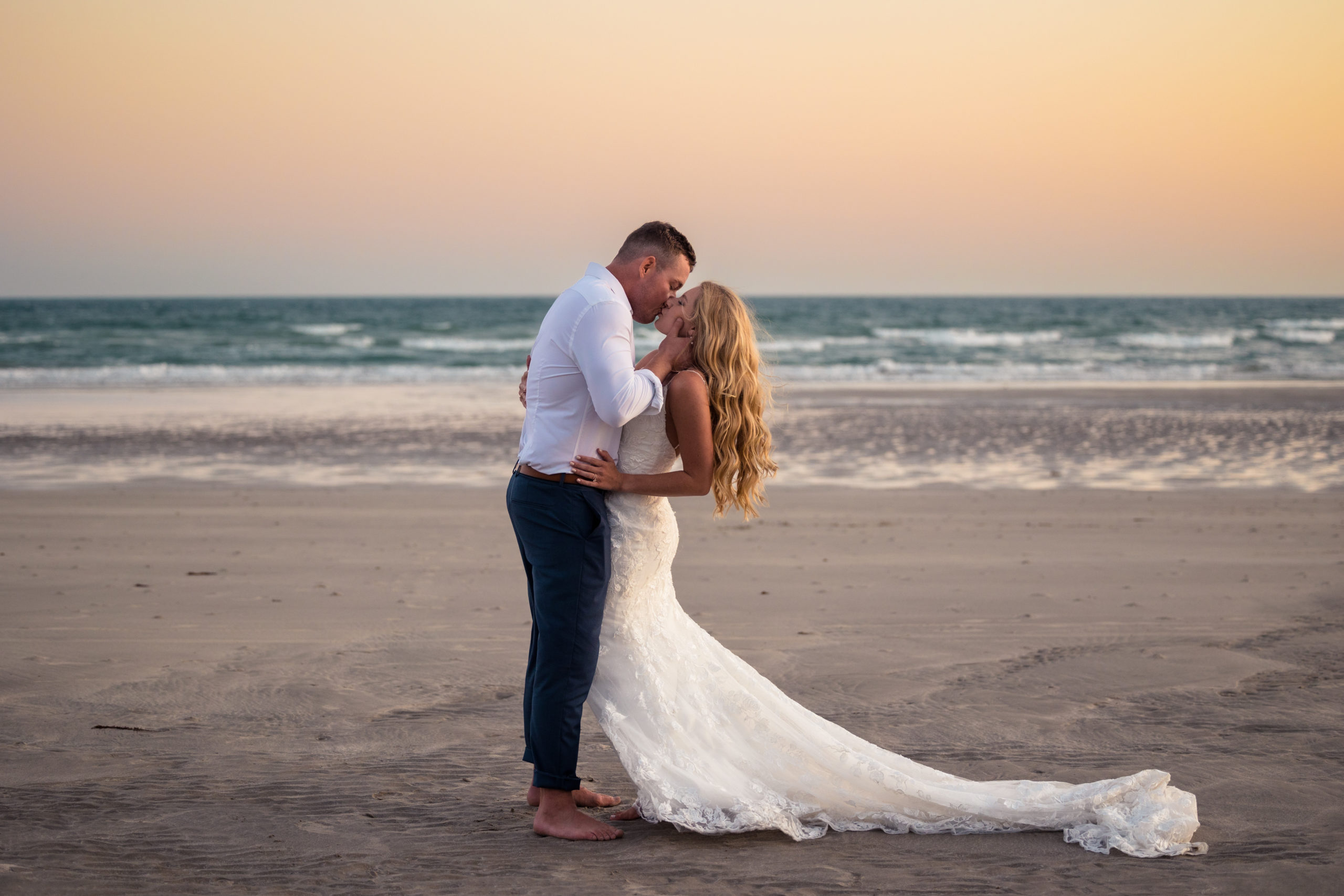 bride and groom kissing on beach in rocky point