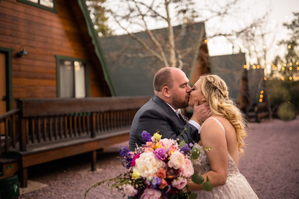 bride and groom kissing in front of cabin