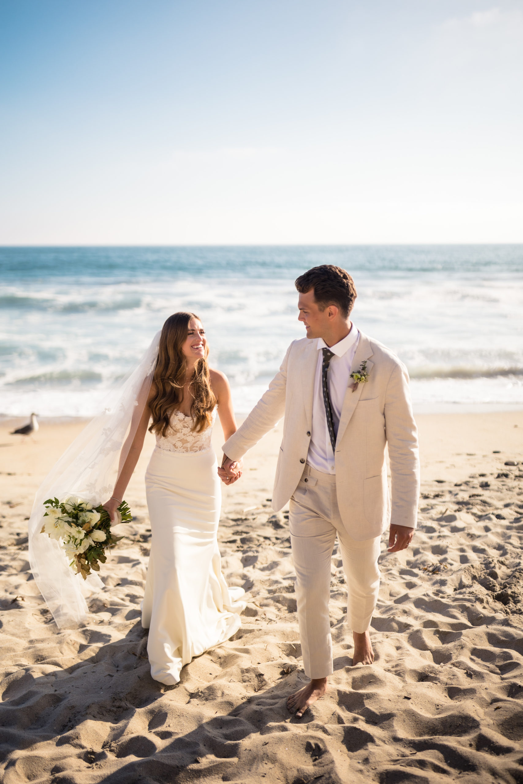 bride and groom walking on carlsbad beach