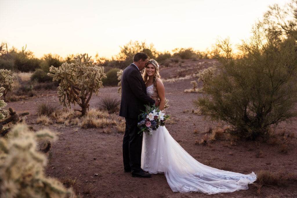 A couple is standing in a sunlight garden of cholla cactuses after their Superstition Mountain elopement.
