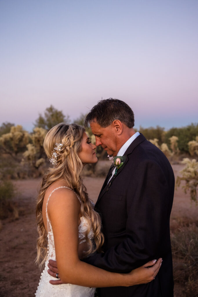 A couple is standing together, facing each other on their elopement day in the Superstition Mountains. they are leaning their foreheads together, eyes closed.