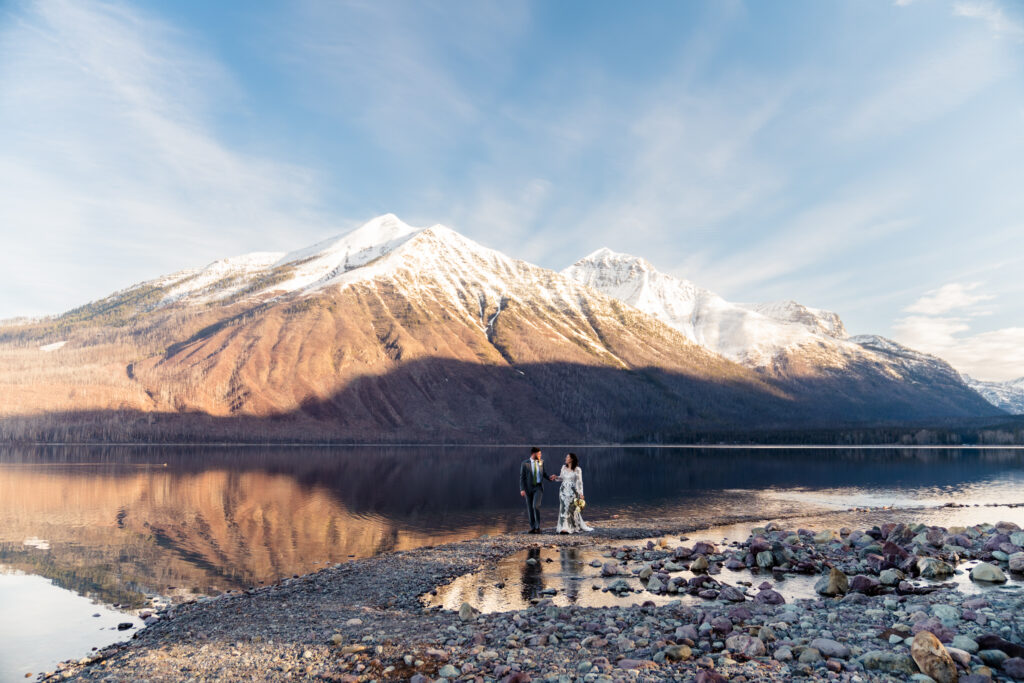 Bride and Groom walking on Lake McDonald Lodge Beach after their wedding ceremony.