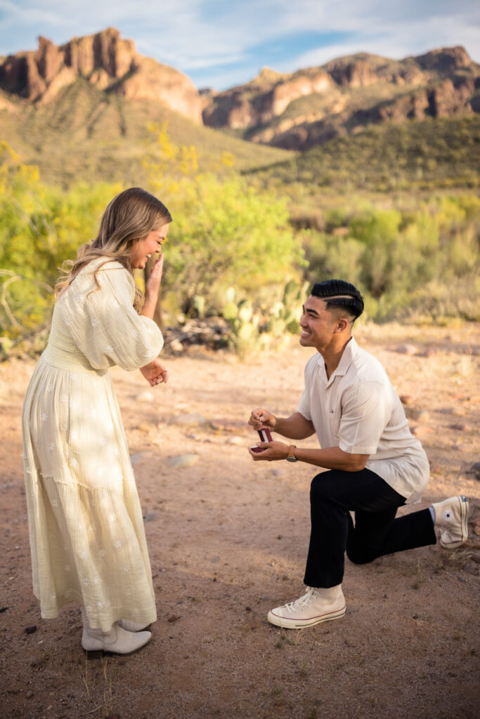 A proposal at Salt River, one of the best places to propose just outside of Phoenix. A man is on one knee holding a ring, while his partner covers her mouth in shock.