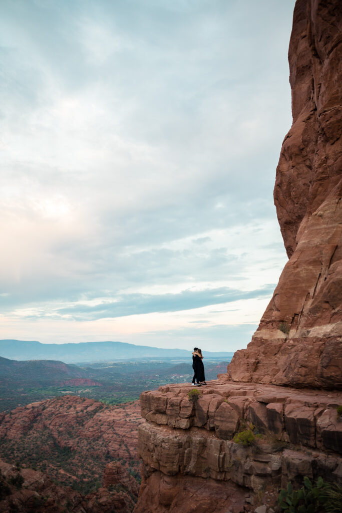 A couple standing on the ledge at Cathedral Rock, hugging each other on their elopement day.