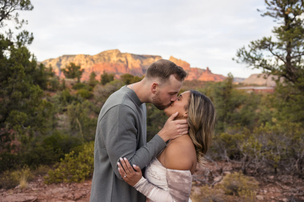 couple kissing after proposal at Mariposa Grill in front of the sedona red rocks