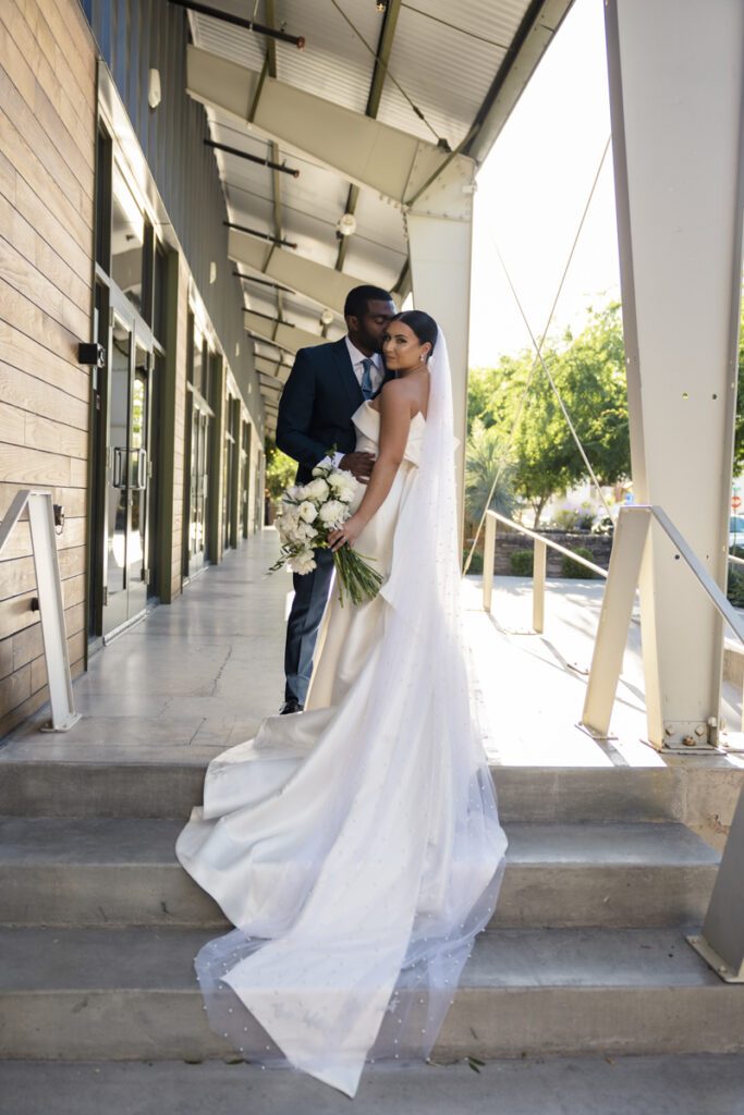 Groom kissing bride while her dress train sits on the stairs