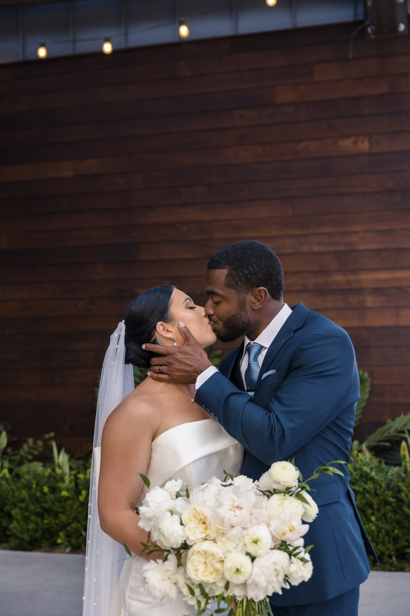 bride and groom kissing in front of wood wall