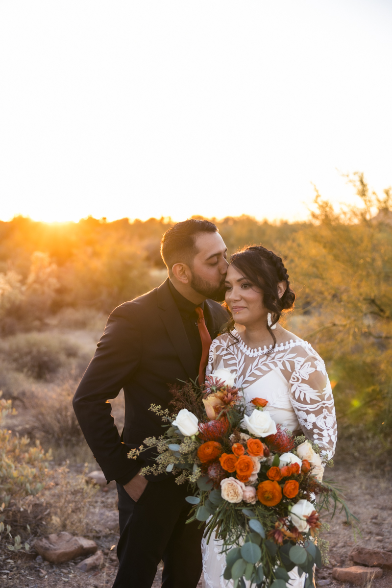 groom kissing bride in the desert