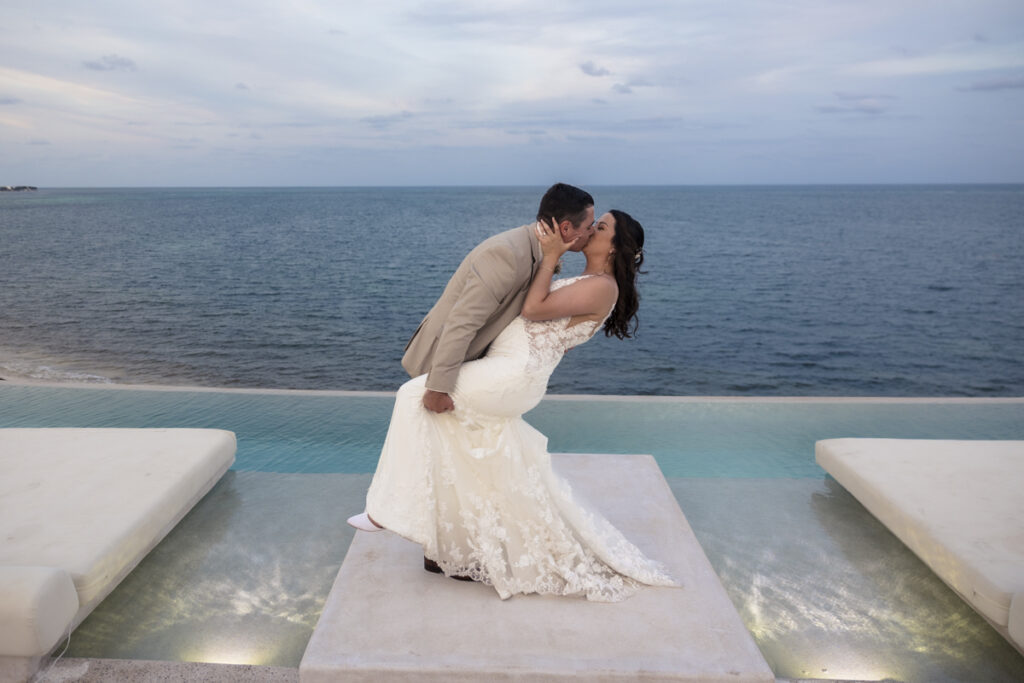 bride and groom kissing on rooftop pool