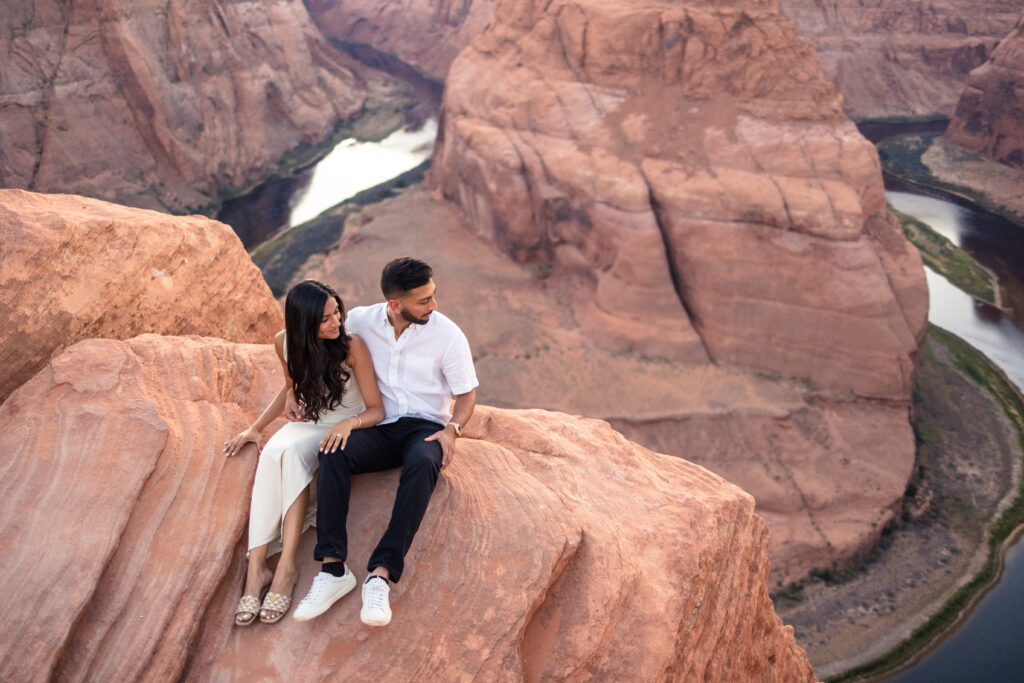 bride and groom sitting on the edge of horseshoe bend