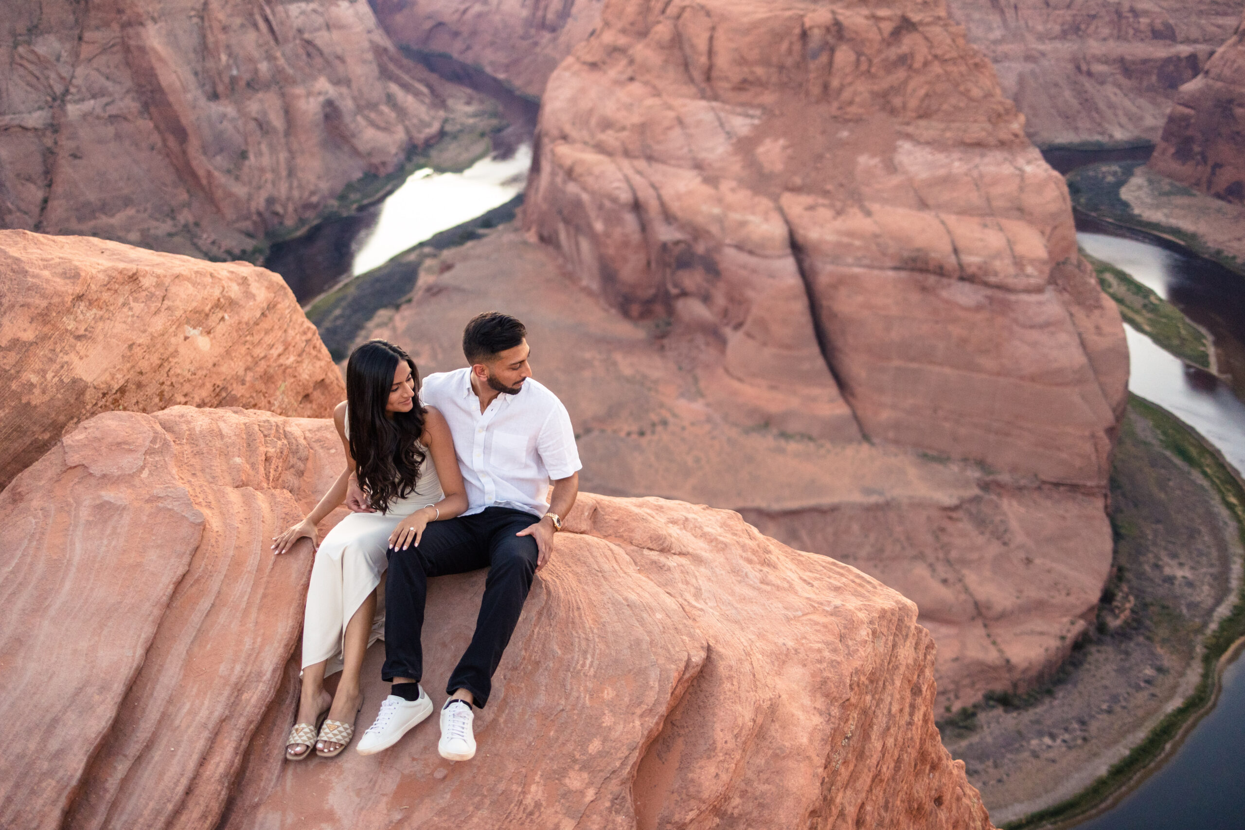 bride and groom sitting on the edge of horseshoe bend