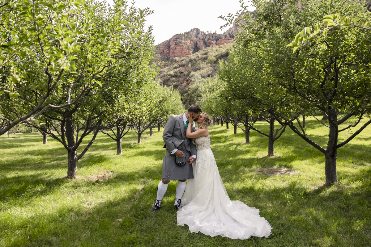 bride and groom kissing in orchards