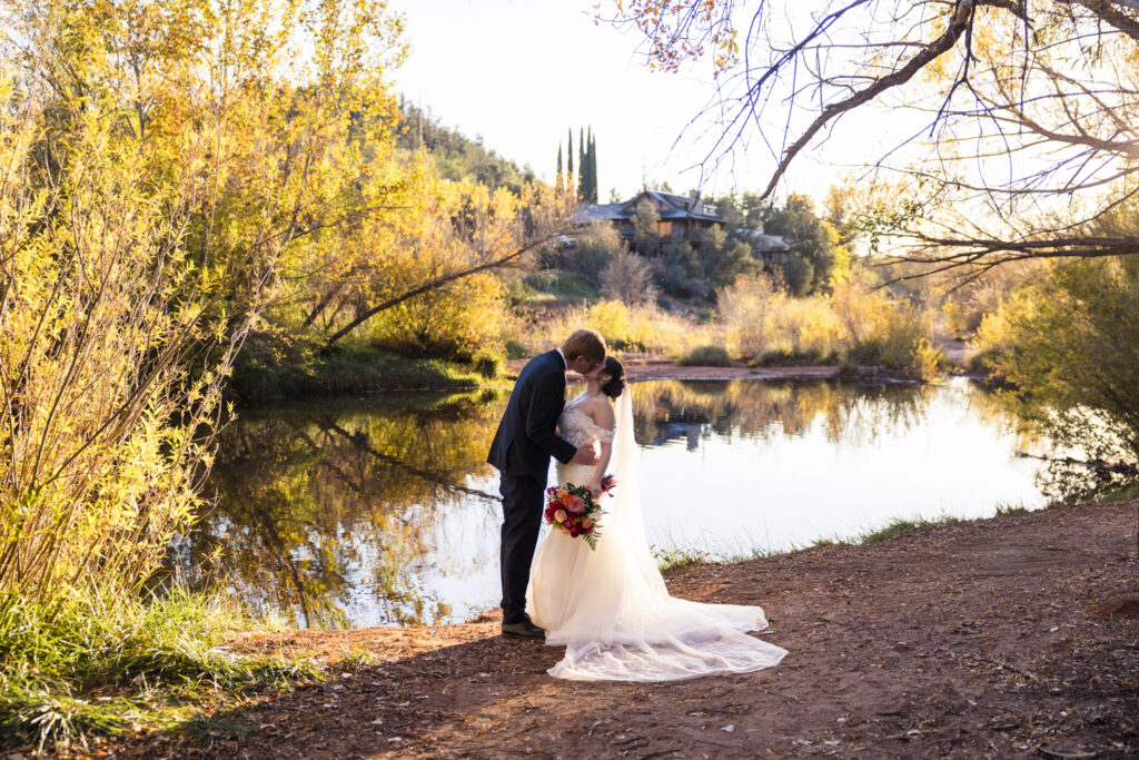 bride and groom kissing in front of oak creek